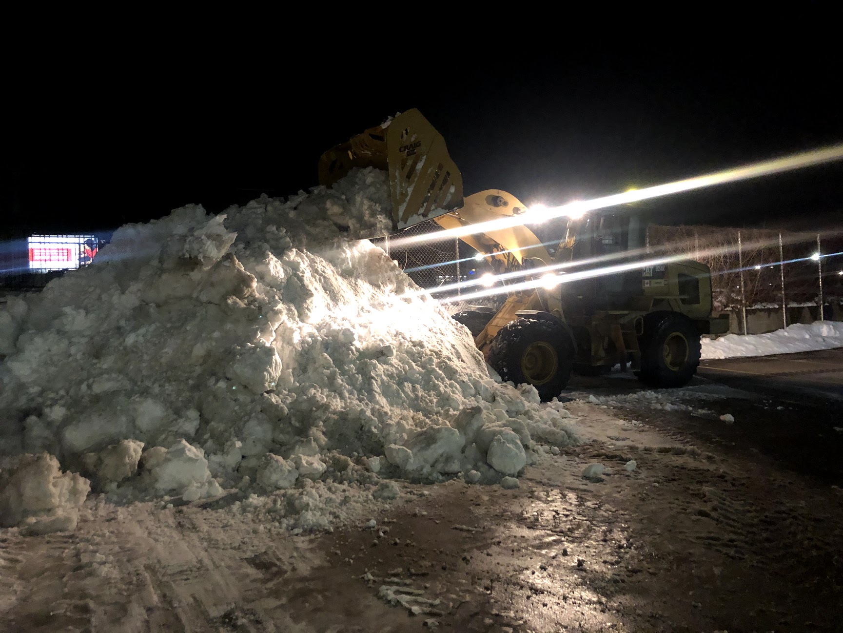 A frontend loader moving a large mound of snow.