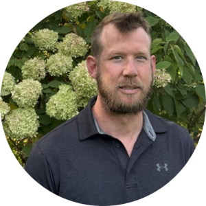 A man standing in front of a tree smiling.